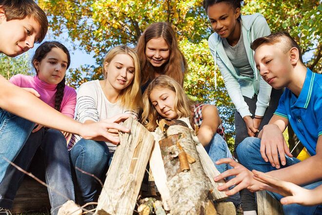 Jugendliche in einem Wald blicken auf Holzstücke